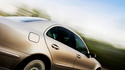 Silver sedan car in motion driving fast along a open road