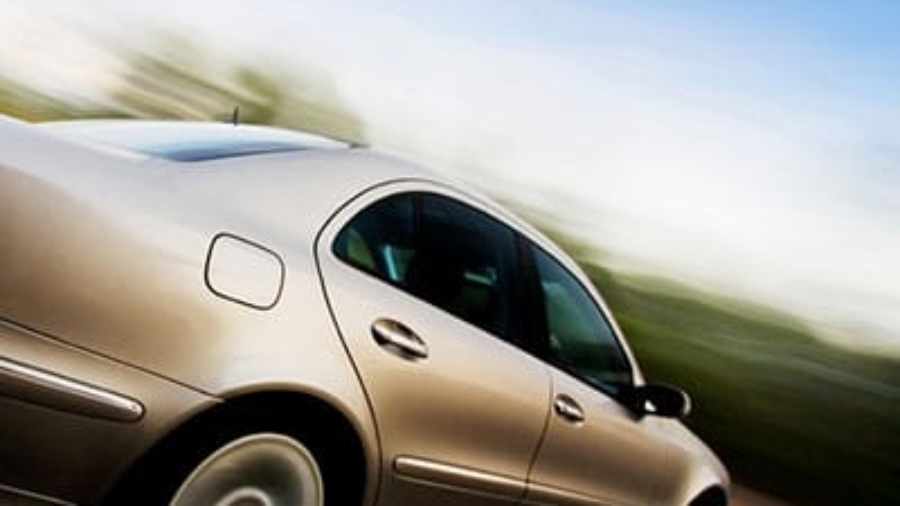 Silver sedan car in motion driving fast along a open road