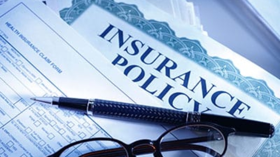 An insurance policy document with a pen and reading glasses resting on top