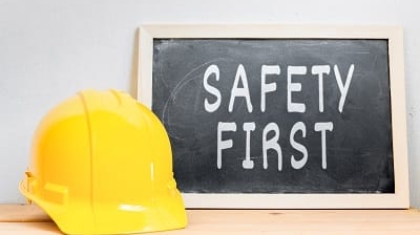 Yellow hard hat placed next to a small chalkboard sign reading Safety First