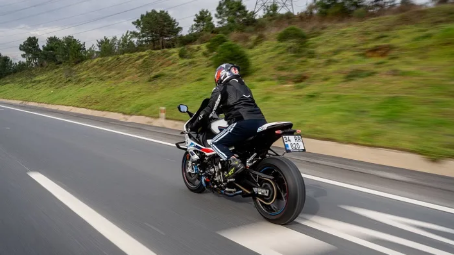 Rider wearing protective gear and helmet riding a sport motorcycle along a highway
