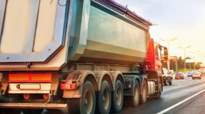 Rear view of a large heavy-duty dump truck driving on a multi-lane highway
