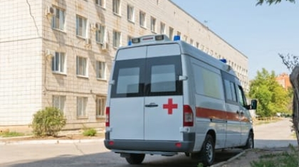 White non-emergency medical transportation van with a red cross logo parked outside a building