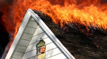 Large orange flames burning through the roof and gables of a residential home