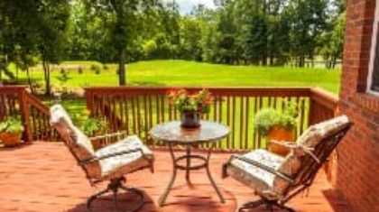 Wooden back deck with outdoor furniture overlooking a green yard