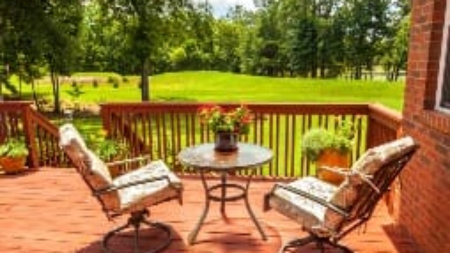 Wooden back deck with outdoor furniture overlooking a green yard