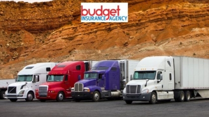 Row of semi-trucks in white, red, and purple parked in front of a desert rock formation