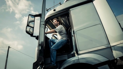 Commercial truck driver stepping up into the cab of a large white semi-truck