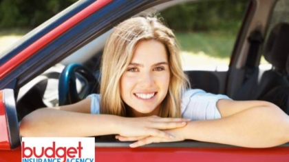 Smiling teenage driver leaning on the open window frame of a red car