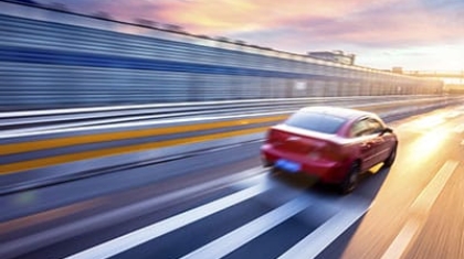 Red car driving at high speed down a highway with motion blur during sunset