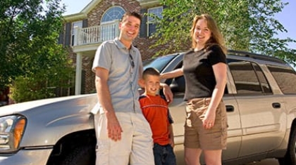 Family standing outside near an SUV in front of a house