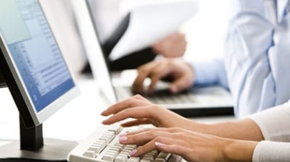Close-up of an office worker typing on a computer keyboard to check driving record reports