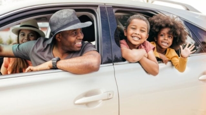 Happy African American family leaning out of car windows and smiling during a road trip