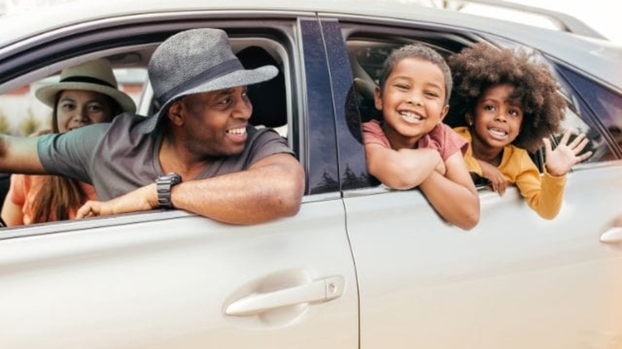Happy African American family leaning out of car windows and smiling during a road trip