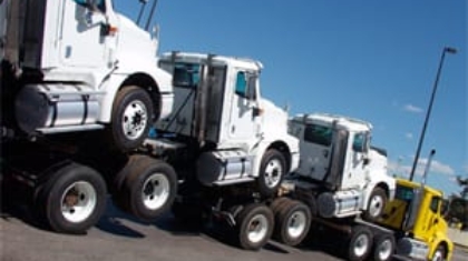 Large multi-car transporter truck carrying several commercial semi-truck cabs on a sunny day