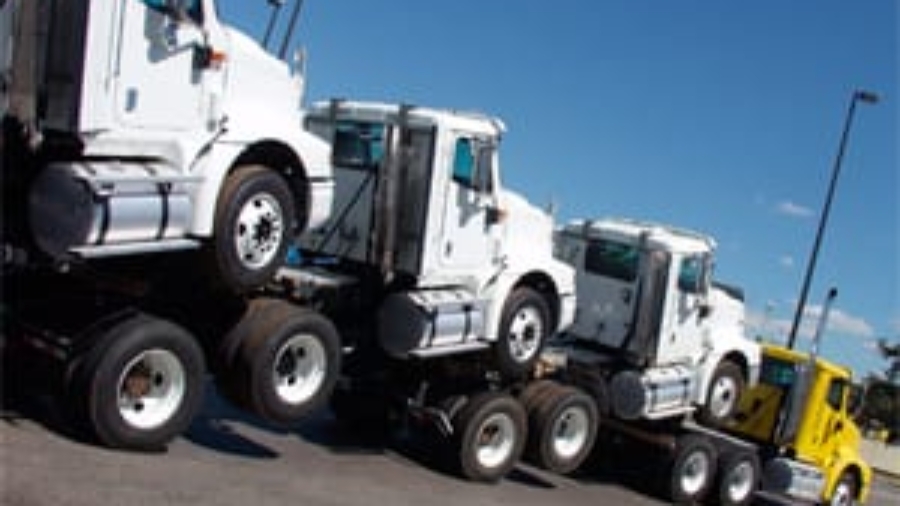 Large multi-car transporter truck carrying several commercial semi-truck cabs on a sunny day