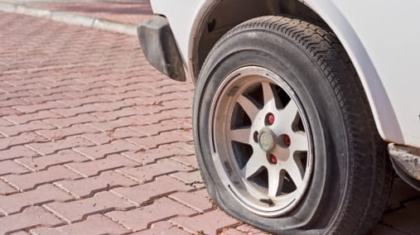 Close-up view of a flat car tire parked on a paved stone surface