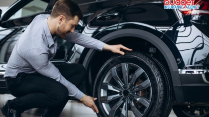 Man crouching down and inspecting the tire and wheel of a black car
