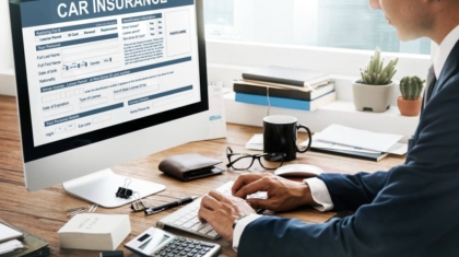 Man in a suit using a desktop computer to complete an online car insurance application form