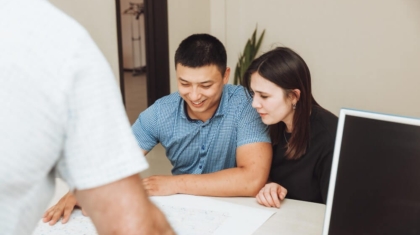 Young couple reviewing home insurance plans with an agent across a desk
